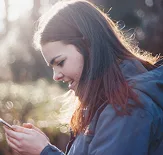 a woman smiling at her phone